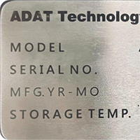 A metal equipment nameplate with model and serial number text.